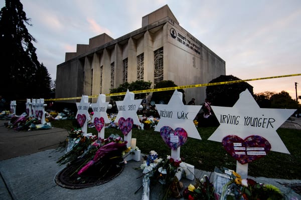 Several white Stars of David stand in front of the synagogue, each with the name of a victim of the shooting.